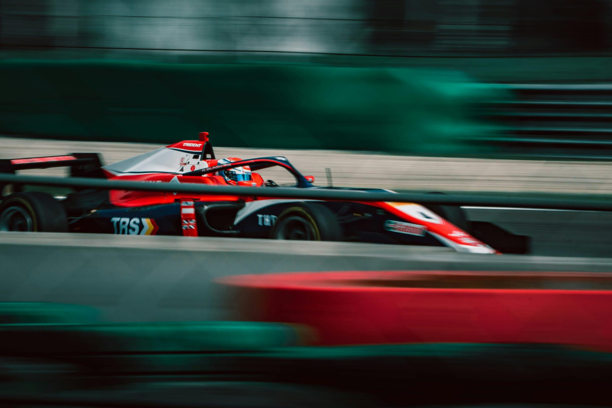 A single-seater at racing speed, the circuit behind it drawn into streaks by the panning camera.