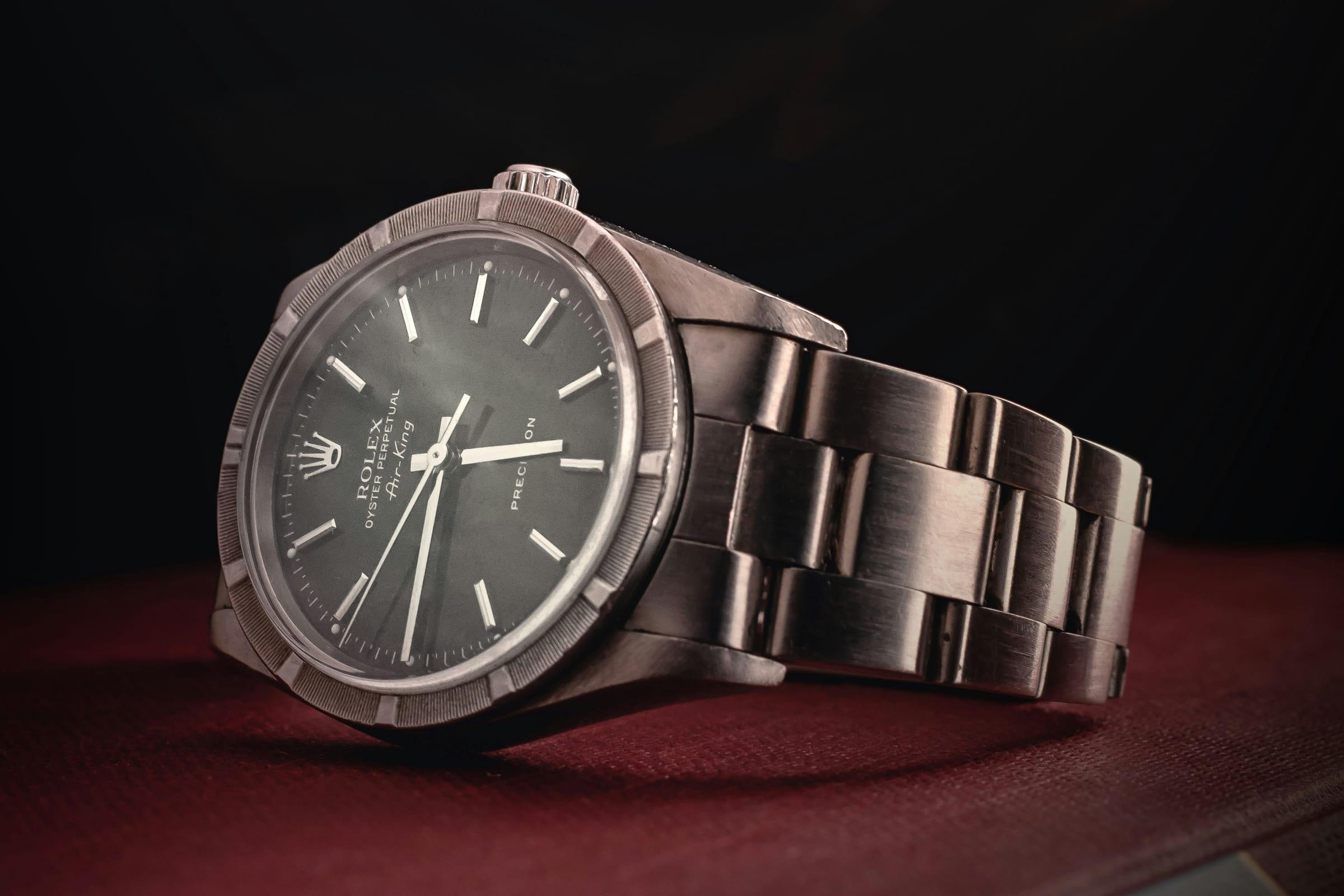 A steel wristwatch on its bracelet, the dial lit from one side against a dark ground.