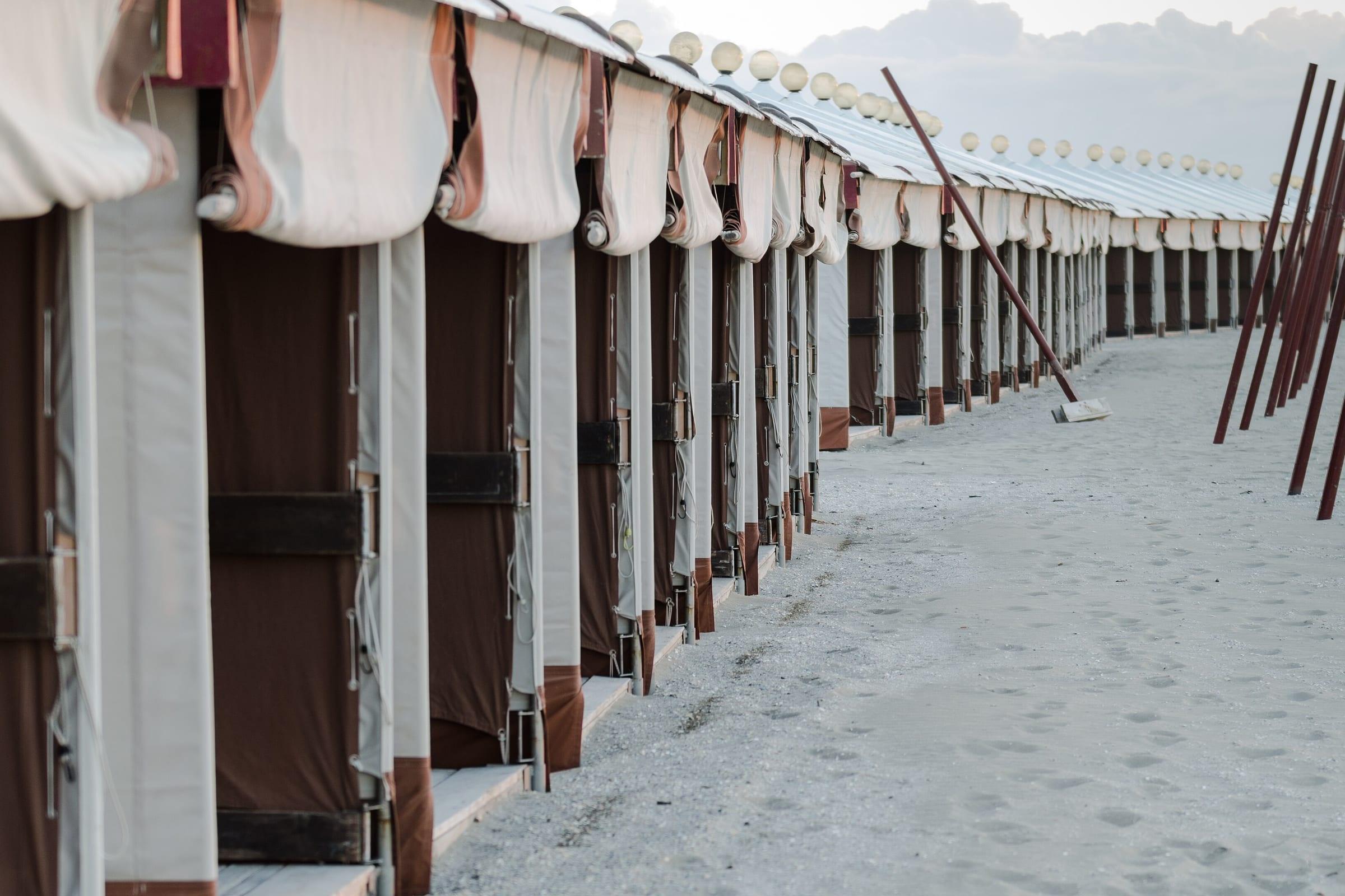 The white bathing cabins along the beach at the Lido di Venezia, sand in front of them.