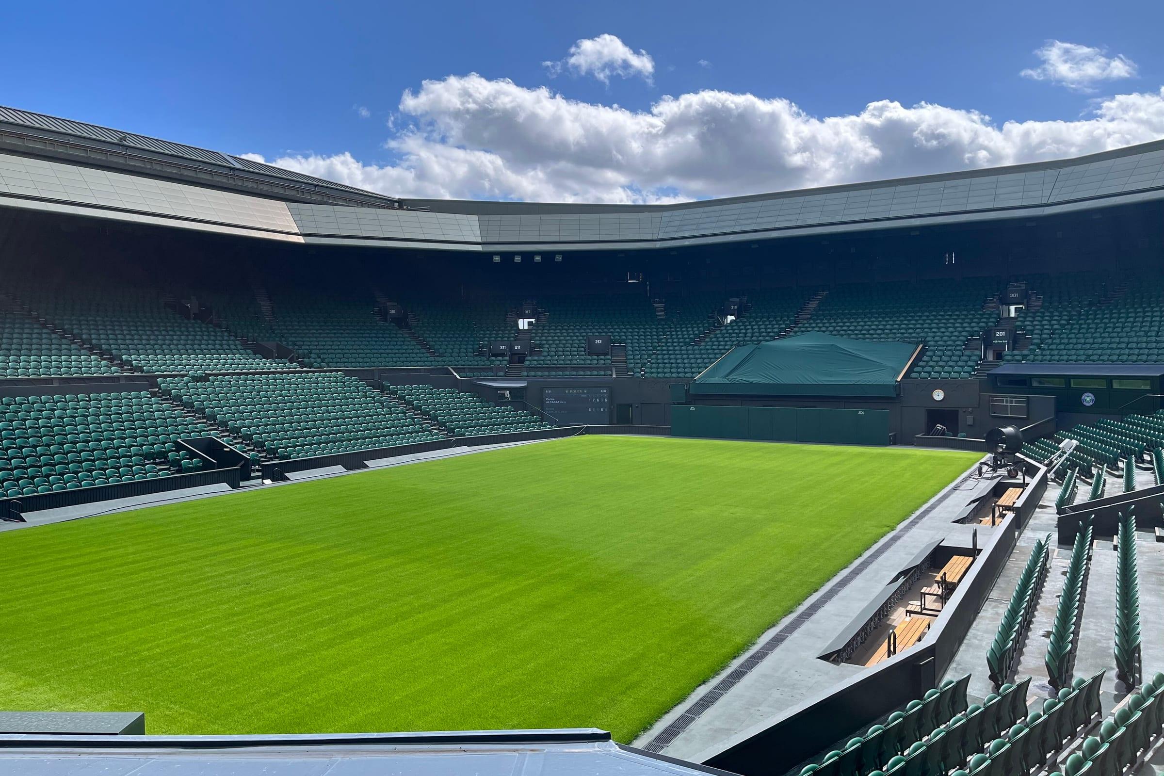 Centre Court at Wimbledon, the grass mown in stripes and the empty stands rising around it.