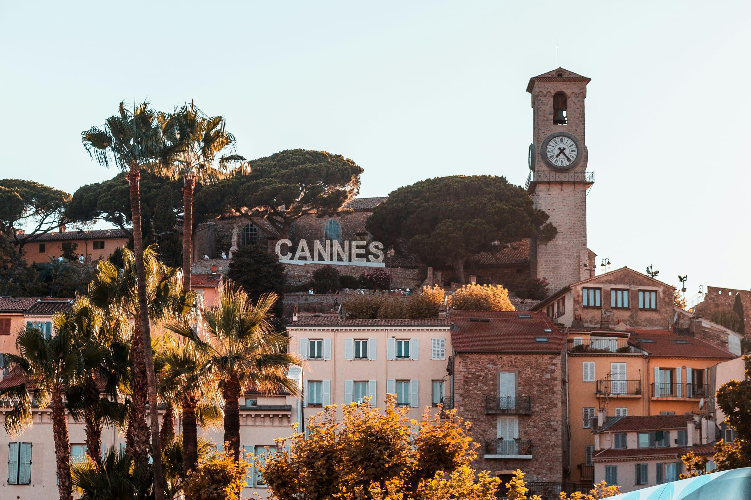 The old town at Cannes above the bay, its clock tower and terracotta roofs among umbrella pines.