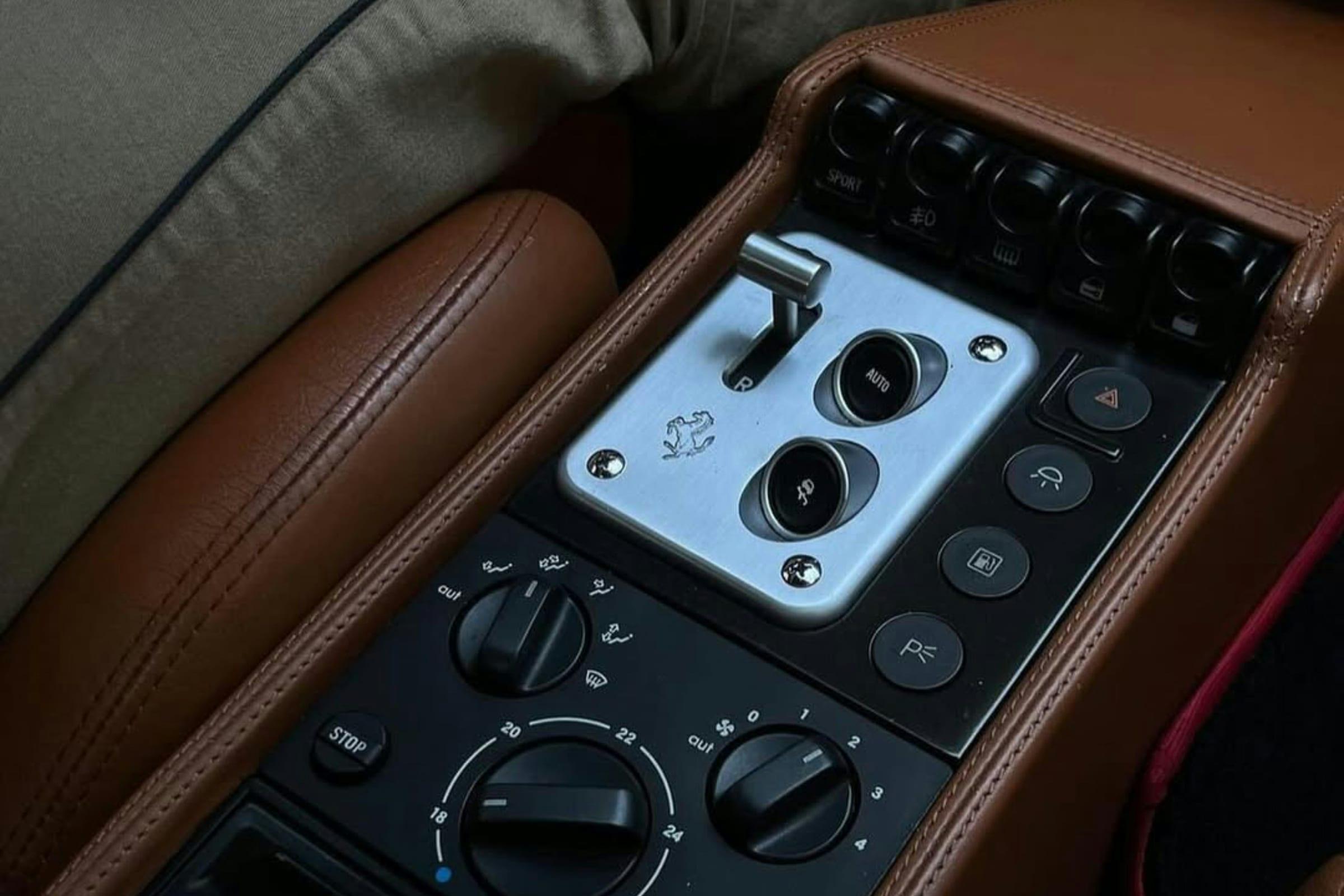 The centre console of a classic grand tourer, chrome switchgear set into tan leather.