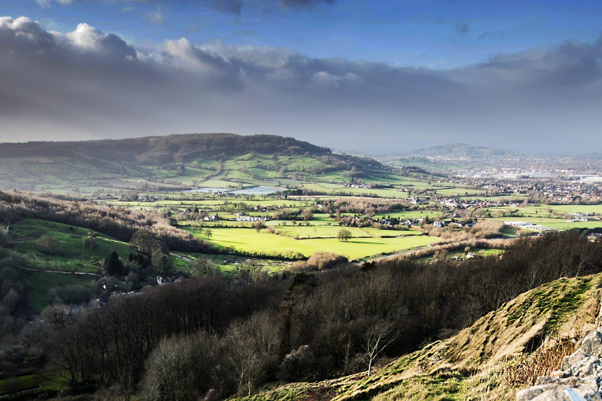 The Cotswold escarpment above Cheltenham, pasture and woodland falling away to the vale.