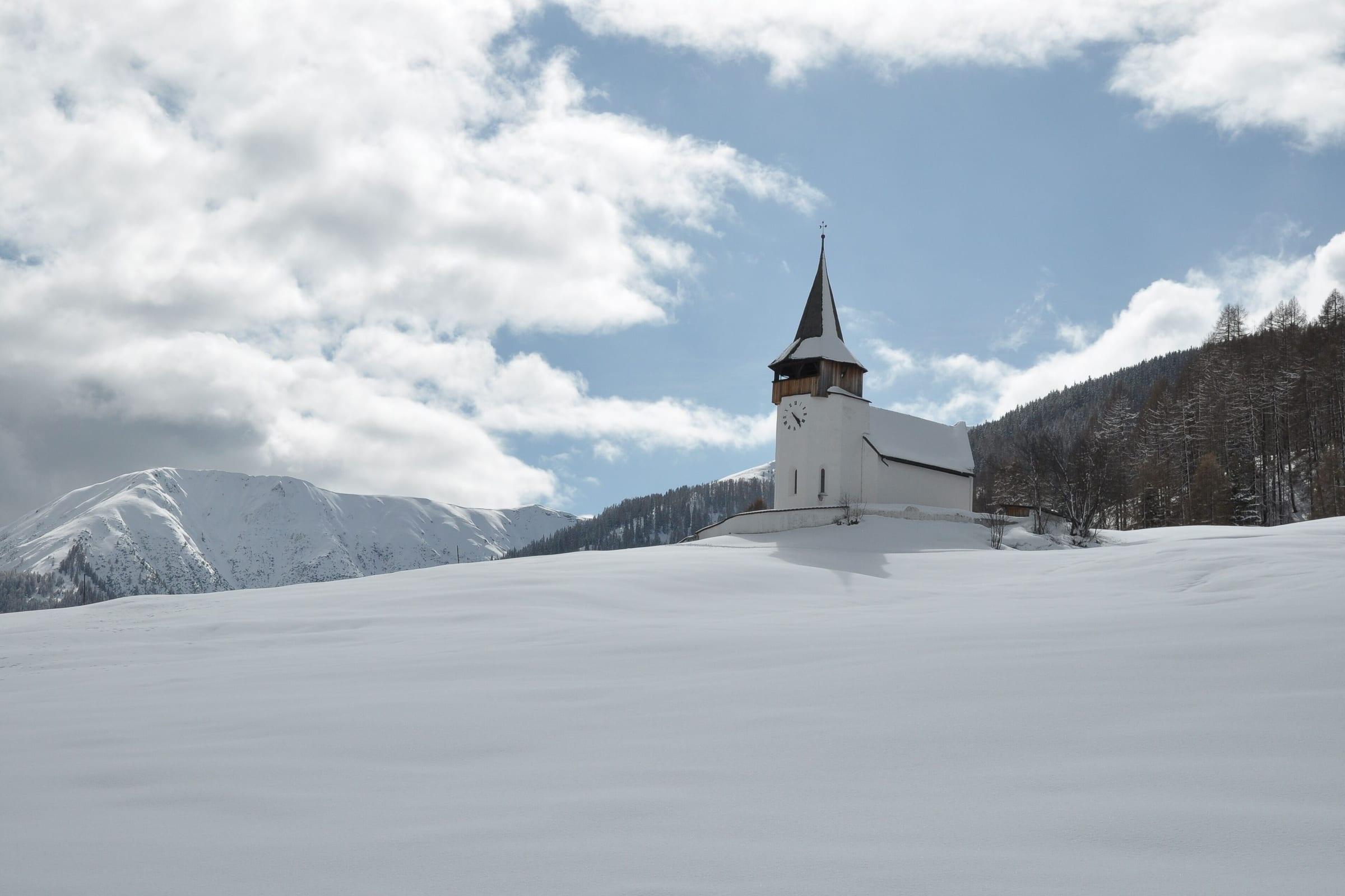 The church at Frauenkirch above Davos, deep snow across the valley and cloud on the peaks behind.