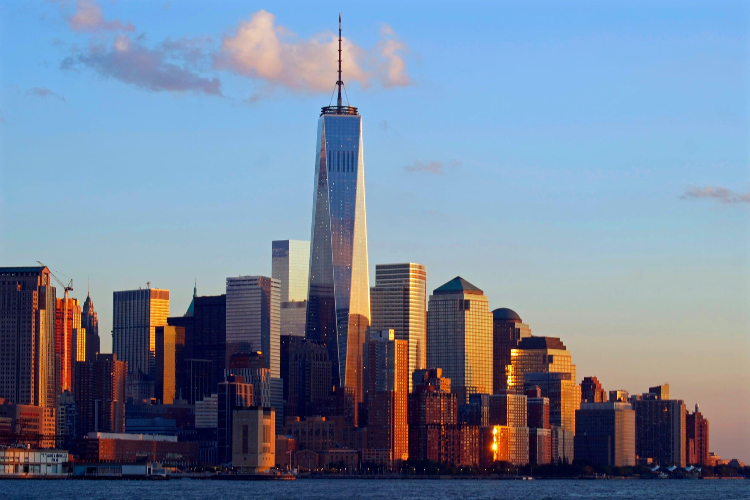 The Lower Manhattan skyline at golden hour, seen across New York harbour.